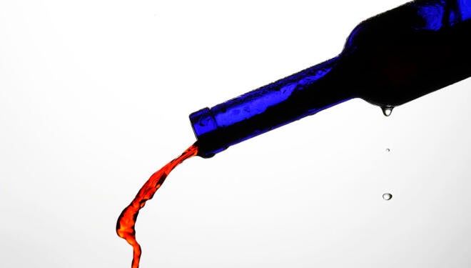 blue bottle pouring red wine against a whitebackground