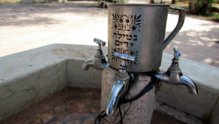 image of an outdoor hand-washing station that has the blessing for washing hands in hebrew