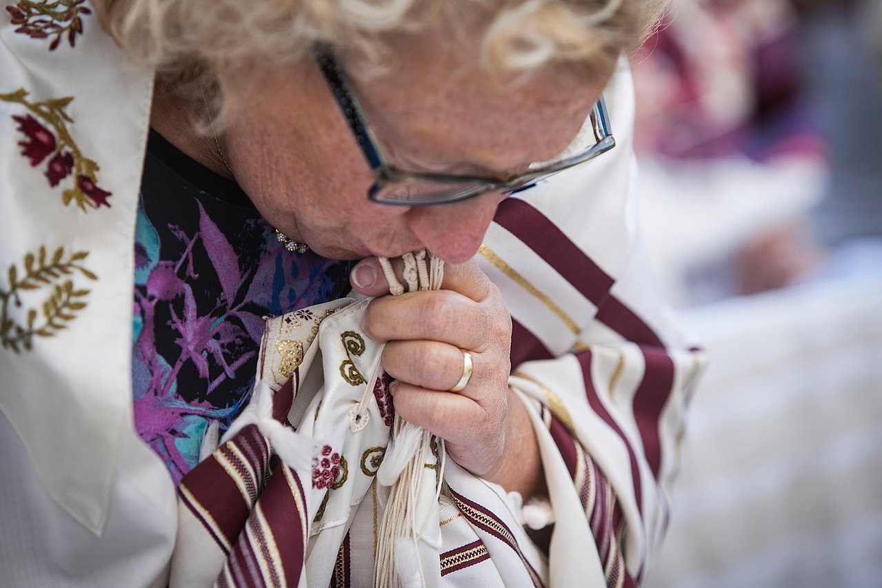 a woman kissing the fringes of a tallit