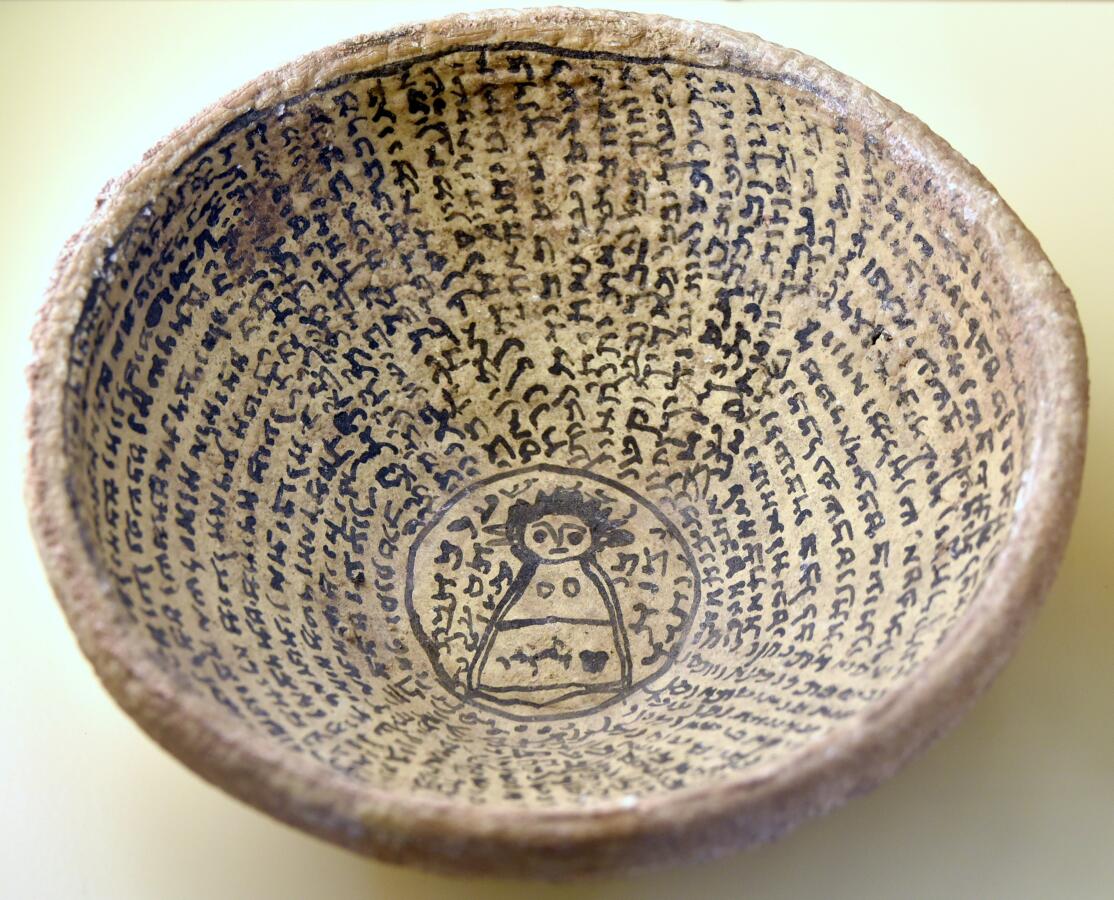 Photo of an ancient bowl with writing and an image of a woman in the center.