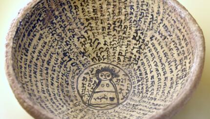 Photo of an ancient bowl with writing and an image of a woman in the center.