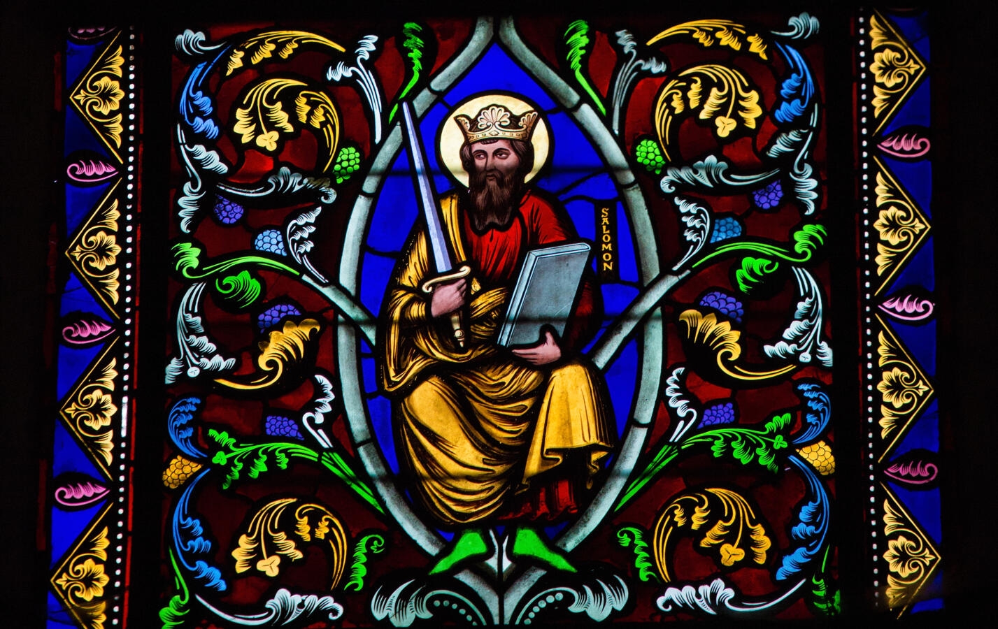 stained glass window depicting a king holding a sword and a book