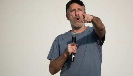 Photograph of a man with a microphone pointing toward the camera.