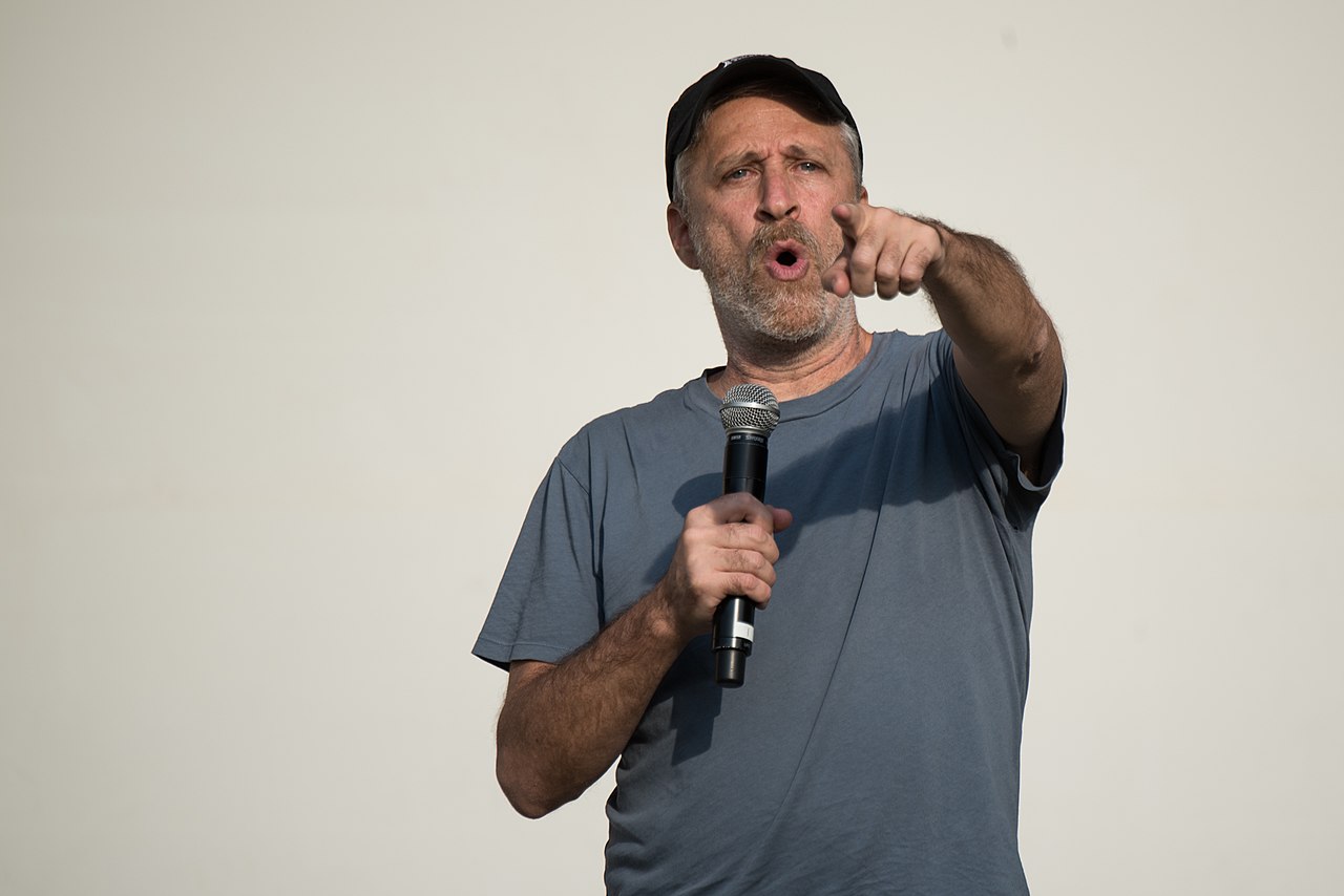 Photograph of a man with a microphone pointing toward the camera.