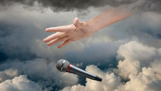 Caucasian hand dropping microphone in clouds