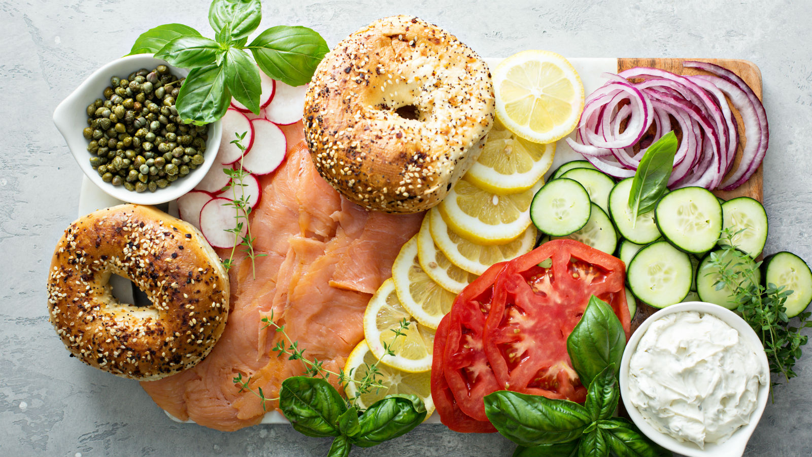 Bagel board with salmon, capers, cream cheese, lemons, vegetables