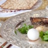 Elements of a traditional Passover seder, including a seder plate, a Kiddush cup for wine, and matzah. The seder plate includes symbolic foods that are related to the Exodus.