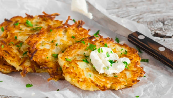 close up photo of latkes with sour cream and chives