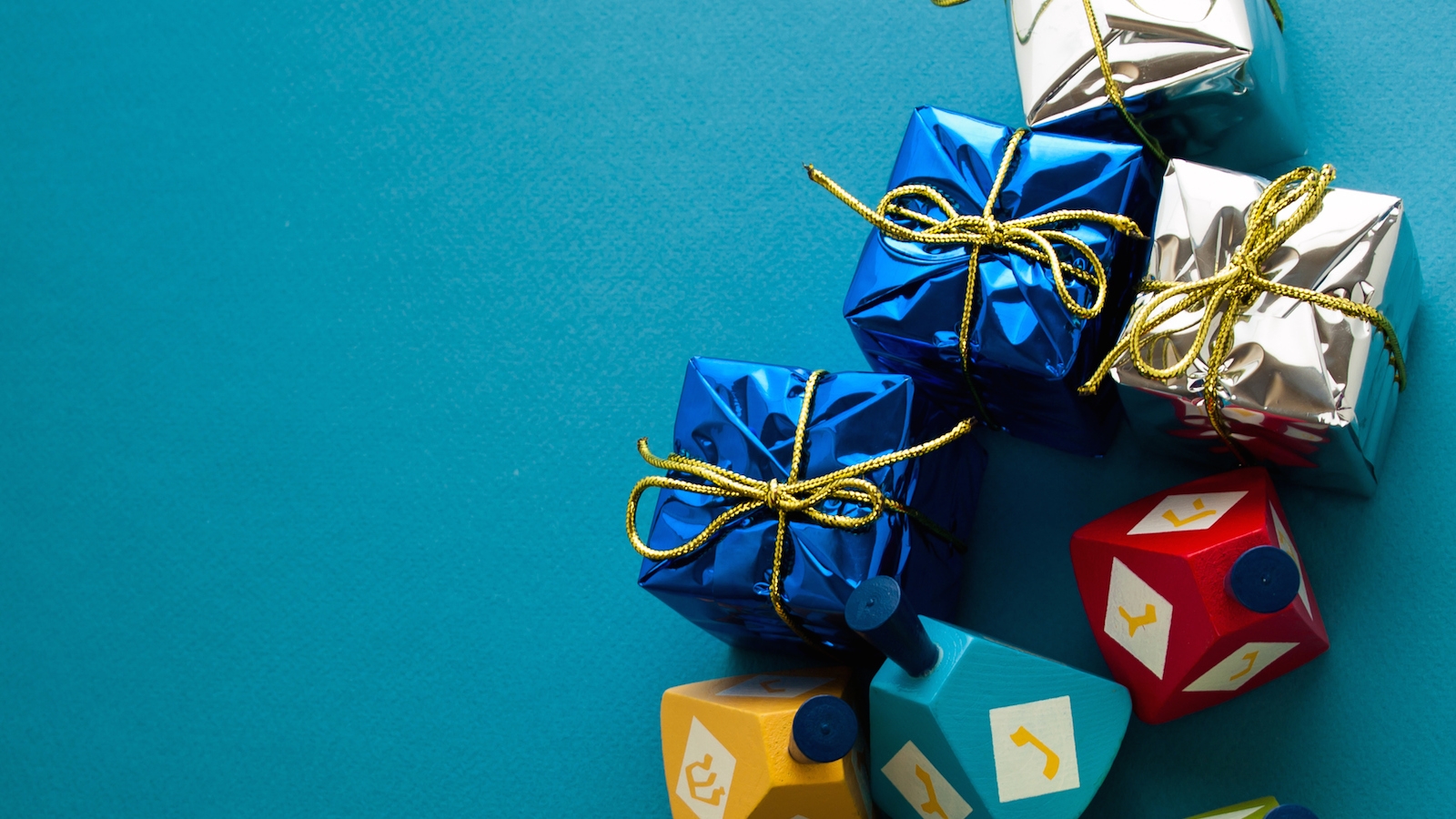 Colorful dreidels with presents on blue background.