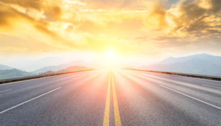 asphalt road and mountains with foggy landscape at sunset