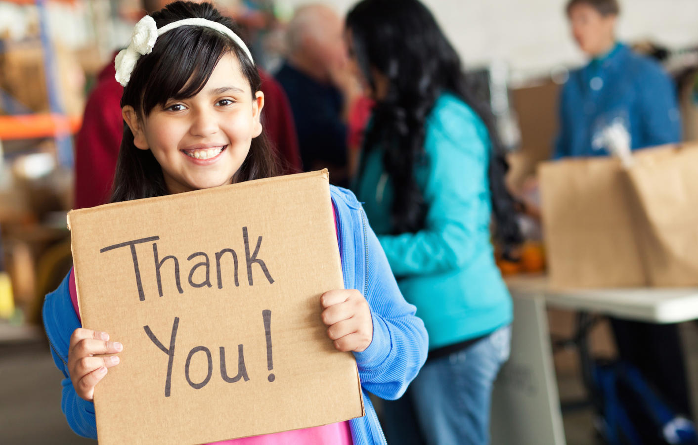 Adorable little girl holds thank you sign during food drive