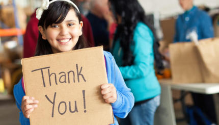 Adorable little girl holds thank you sign during food drive