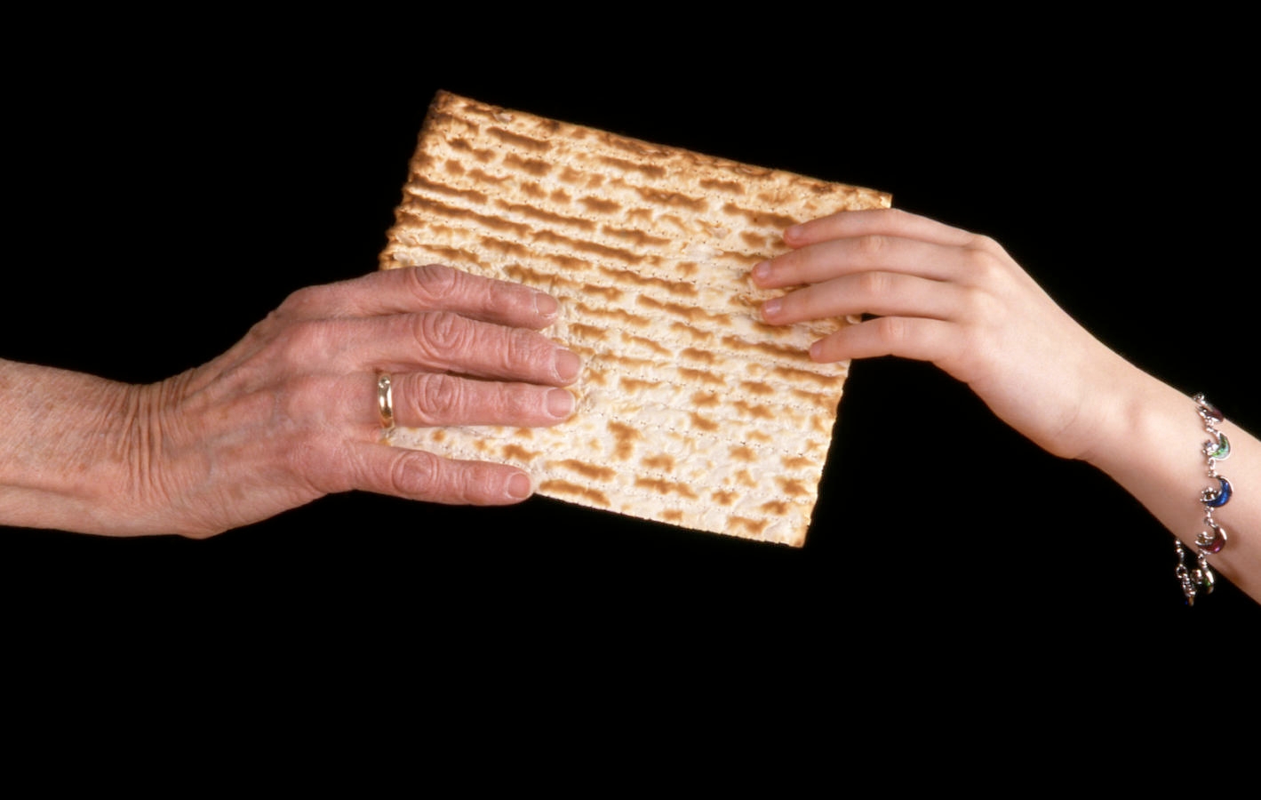 Handing a matzo from an old hand to a young hand.