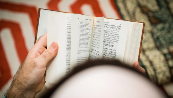 Jewish male wearing Kippah reading Machzor praying book