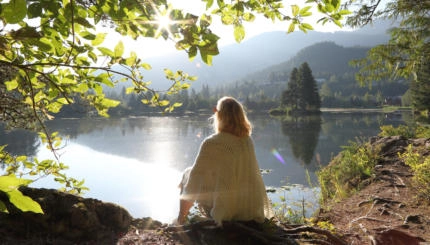 He looks off to distant mountain, forest and lake scene