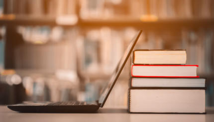 Bookshelves and laptops are placed on the library desk.E-learning class and e-book digital technology