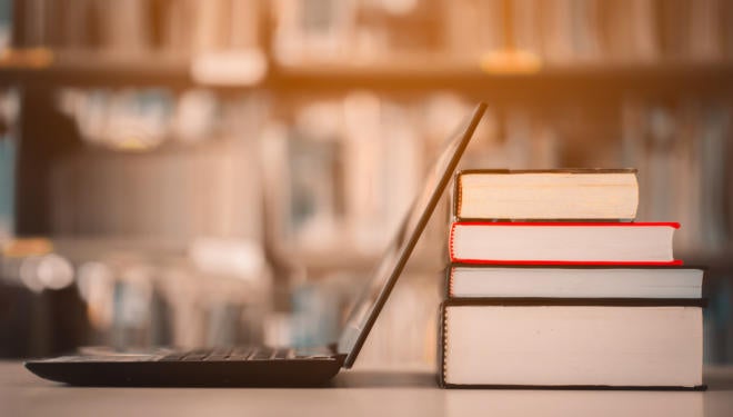 Bookshelves and laptops are placed on the library desk.E-learning class and e-book digital technology