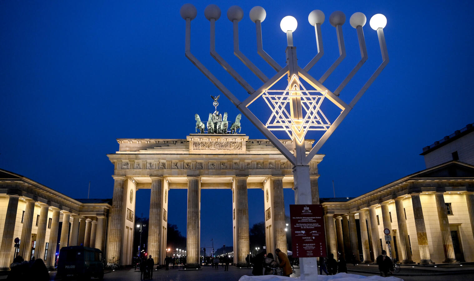 Two lights and the star shine on the Hanukkah chandelier in front of the illuminated Brandenburg Gate.