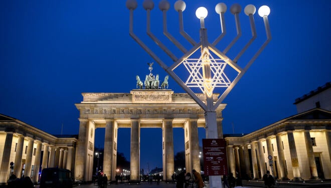 Two lights and the star shine on the Hanukkah chandelier in front of the illuminated Brandenburg Gate.