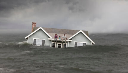 Family sitting on roof of house floating in sea