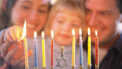 picture of family lighting hanukkah candles