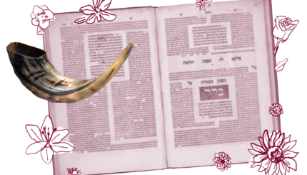 A shofar in front of an open volume of Talmud.