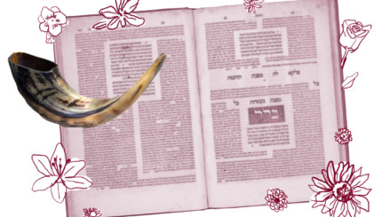 A shofar in front of an open volume of Talmud.