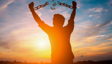 Silhouette image of a businessman with broken chains in sunset