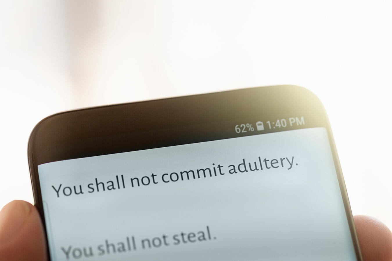 A text message displayed on a mobile phone screen from the Bible's Ten Commandments "You shall not comit adultery"