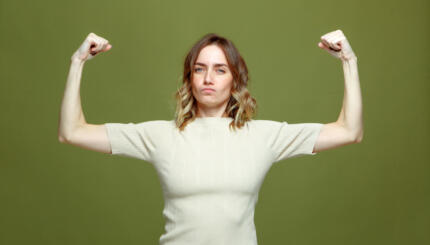 Self confident serious young woman show muscle, strength and independence, raised arms. Girl power, feminism concept. High quality photo