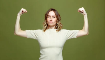 Self confident serious young woman show muscle, strength and independence, raised arms. Girl power, feminism concept. High quality photo