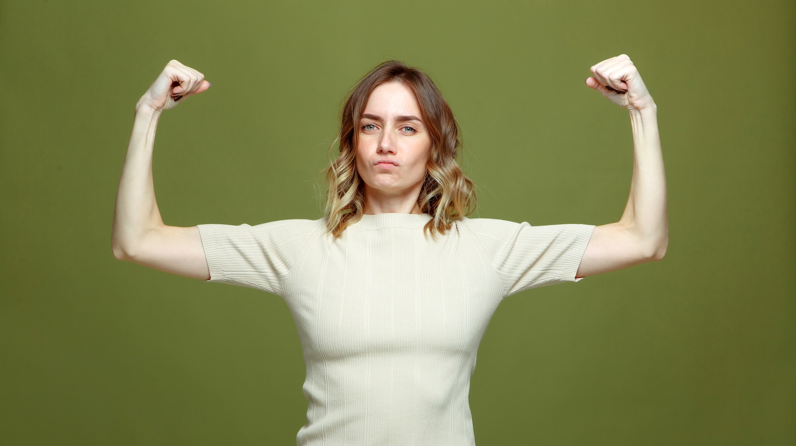 Self confident serious young woman show muscle, strength and independence, raised arms. Girl power, feminism concept. High quality photo