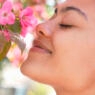 young mixed race woman holding cherry blossoms and smelling it