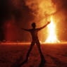 BLACK ROCK DESERT, UNITED STATES: A "Burning Man" participant holds up his arms as the wooden man effigy is burned at the conclusion of the week-long "Burning Man Festival" 06 September in the Black Rock Desert in the northwestern part of the state of Nevada. More than 15,000 people congregated at this man-made town in the desert to celebrate radical, creative self-expression. AFP PHOTO Mike NELSON/mn (Photo credit should read MIKE NELSON/AFP via Getty Images)