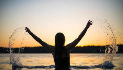 sillhouette of a girl bathing in a river at sunset