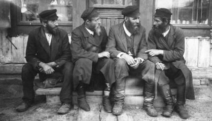 Krasilov, Ukraine (Russian / Polish shtetl or Jewish village ).c. 1916-17. Jewish men sitting outside shop talking