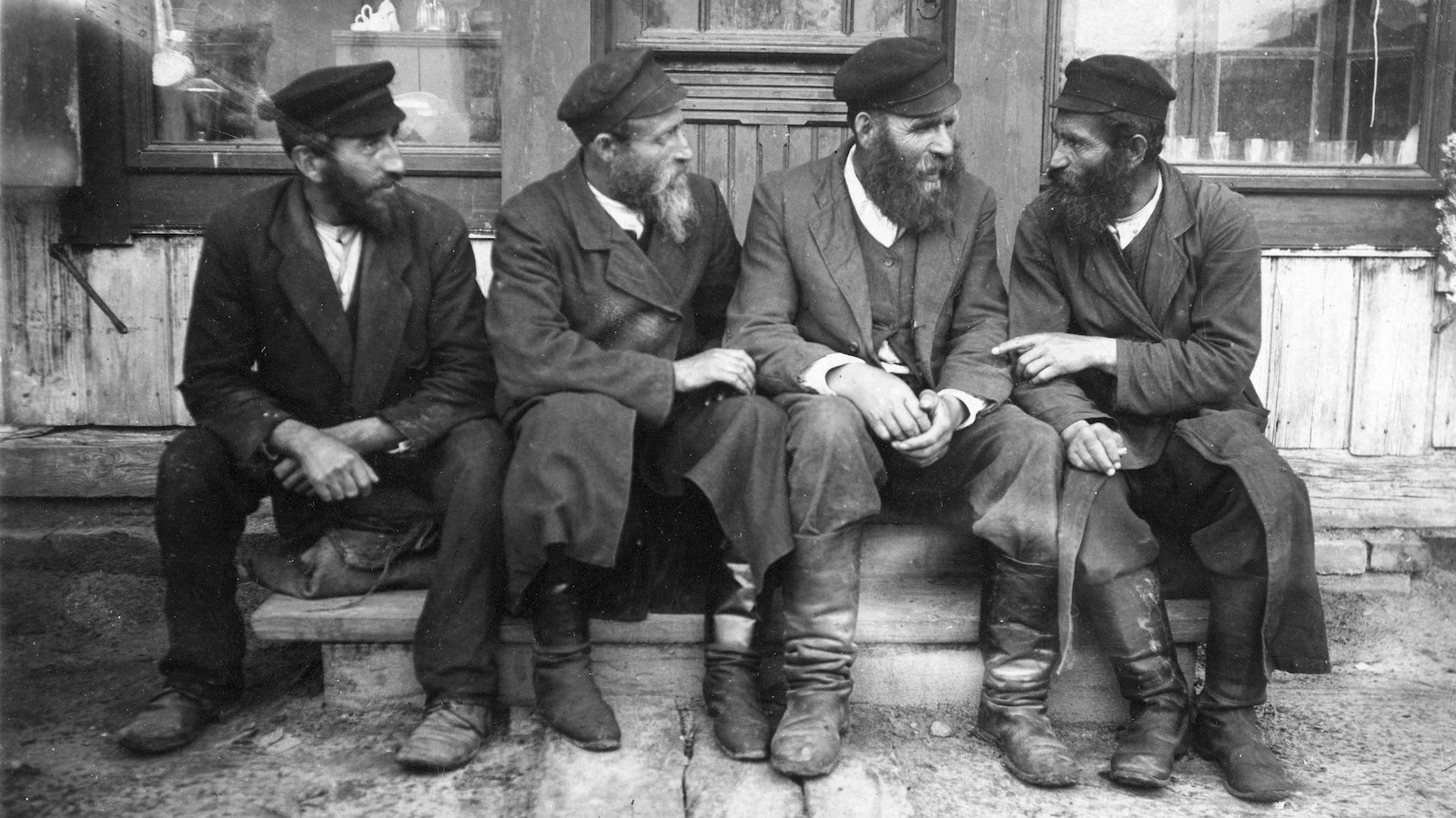 Krasilov, Ukraine (Russian / Polish shtetl or Jewish village ).c. 1916-17. Jewish men sitting outside shop talking