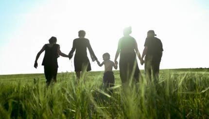 Sillhouette of people in a field holding hands.