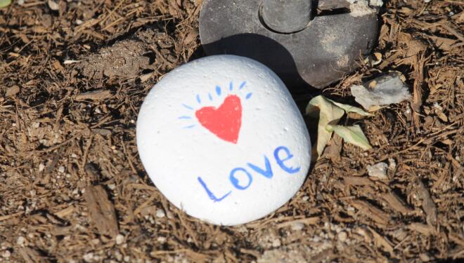 Photo of a white rock with the word love and a heart painted on it.