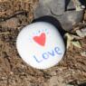 Photo of a white rock with the word love and a heart painted on it.