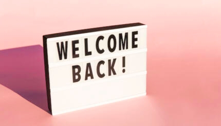 Welcome sign, reopen sign as a greeting to customers or to welcome back students for back to school. This lightbox sign is on a pink background with copy space.