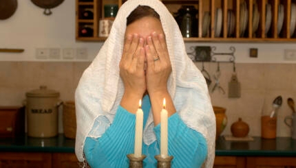 Jewish woman lighting shabbat candles.