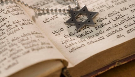 star of david resting on an open torah scroll