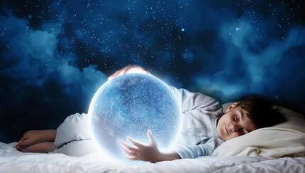 image of a sleeping child holding a full moon with starry sky in background