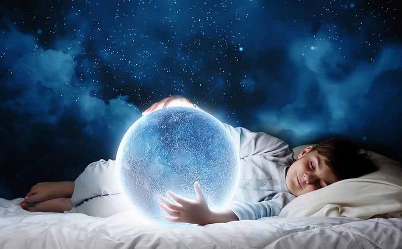 image of a sleeping child holding a full moon with starry sky in background