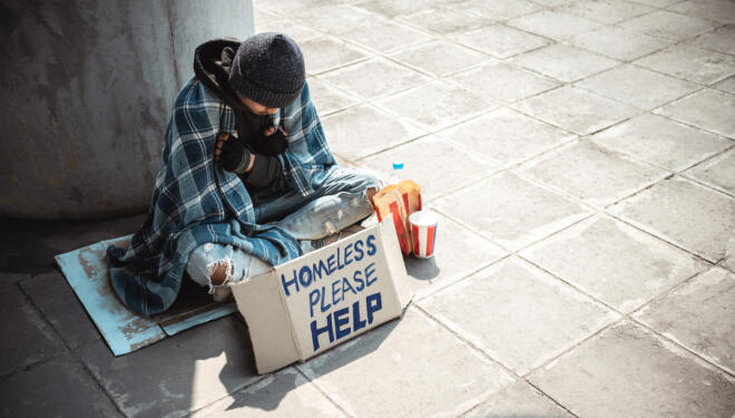 One man, young homeless sitting on the street and begging.