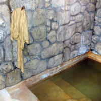 photo of a stone mikveh (ritual immersion pool) with a robe hanging on a peg