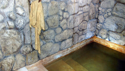photo of a stone mikveh (ritual immersion pool) with a robe hanging on a peg