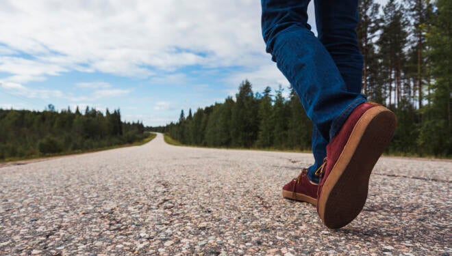 Finland, Lapland, feet of man walking on empty country road