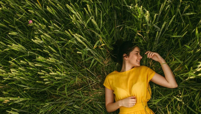 Young girl holding chamomile plant in her hands and enjoying the calm meadow